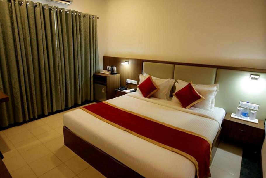 a hotel room with a large bed with red pillows at HOTEL CALICUT GATE in Ferokh