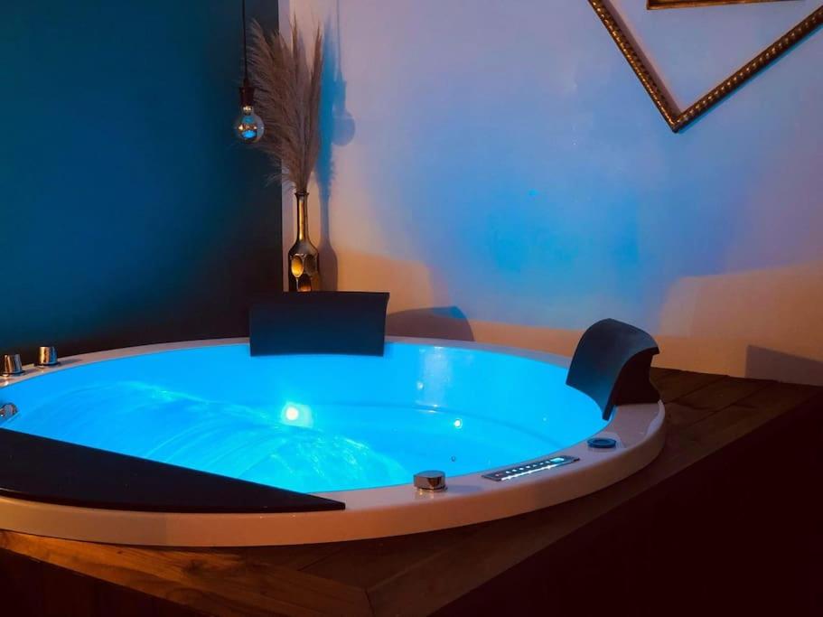 a jacuzzi tub in a room with a blue wall at Loveappart21 l'expérience Bien Être in Dijon