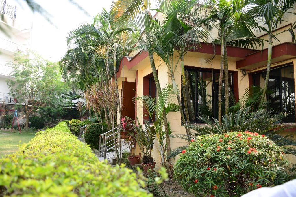 a house with palm trees and plants in front of it at Hotel Dolphin in Digha