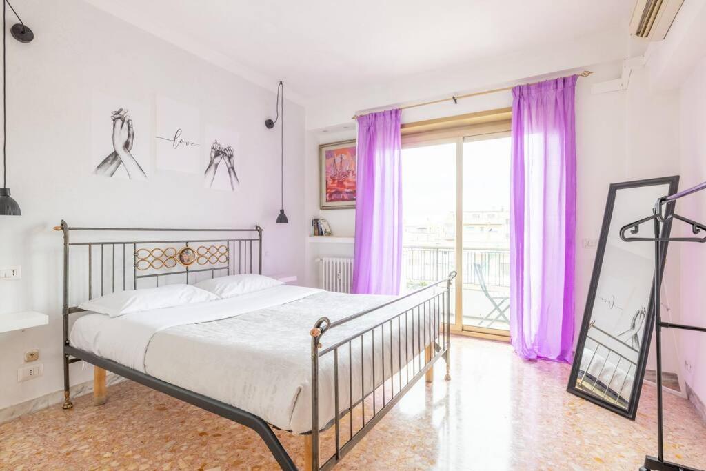 een slaapkamer met een bed met paarse gordijnen bij Ambra's bright apartment in Rome