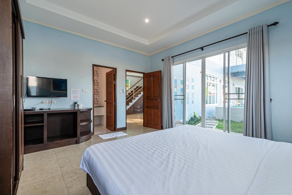 een slaapkamer met een wit bed en een televisie bij Sea TaLay Pool Villa Hua Hin in Hua Hin