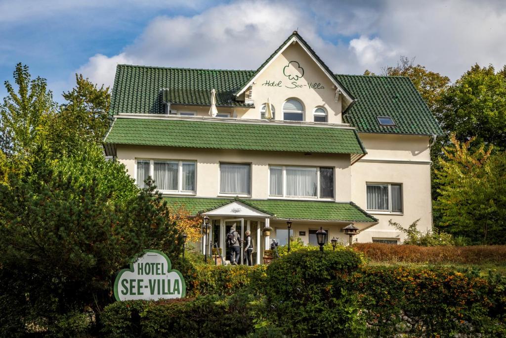 a large white house with a green roof at Hotel See-Villa in Malente