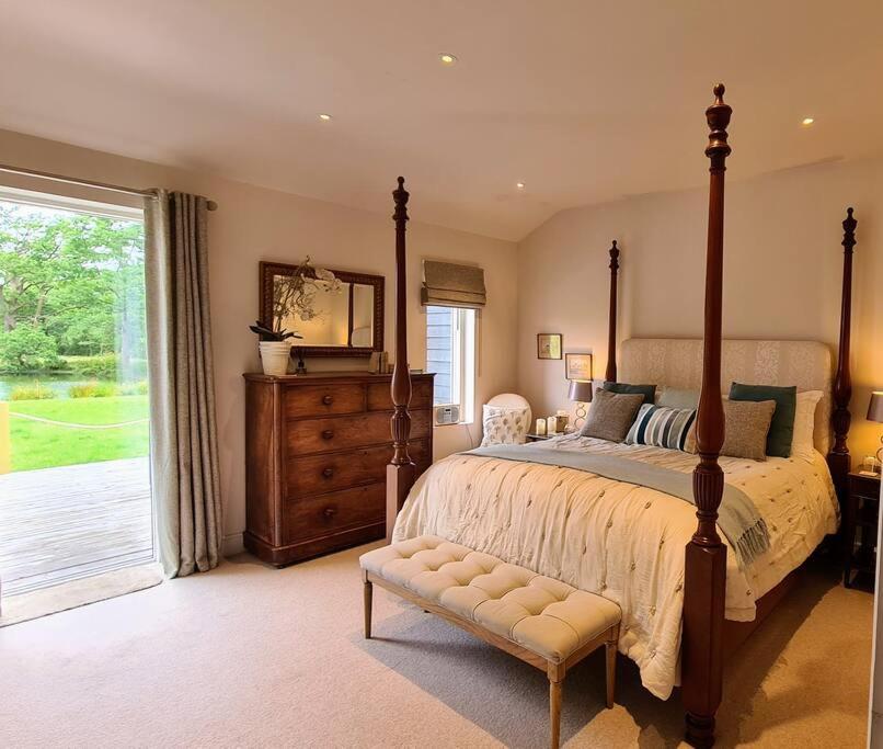 um quarto com uma cama grande e uma janela grande em Luxury 4 poster lakefront rural retreat em Heckfield