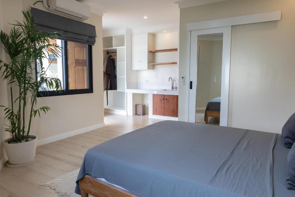 a bedroom with a blue bed and a kitchen at The Nordic House in Bacnotan