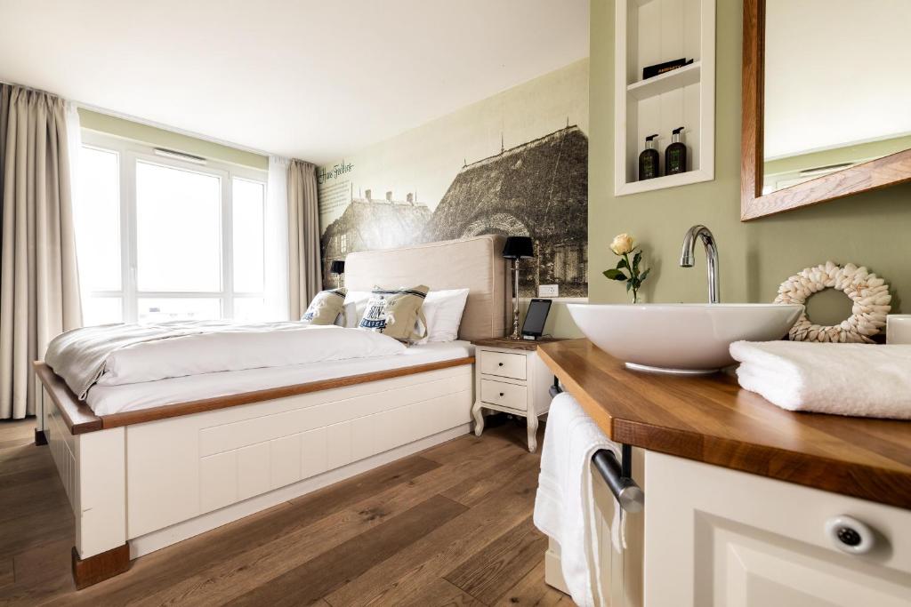 a bedroom with a large bed and a sink at Hotel Zweite Heimat in Sankt Peter-Ording
