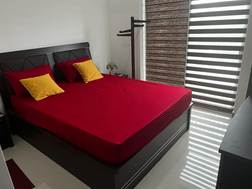 - une chambre avec un lit doté d'oreillers rouges et jaunes dans l'établissement Canterbury Residence Garden Apartments, à Kahatuduwa