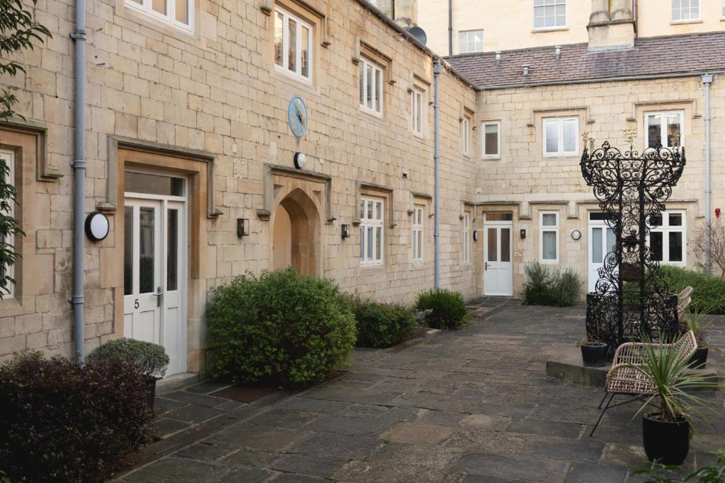 a courtyard of a brick building with benches and plants at St Catherine's Hospital - Curated Property in Bath