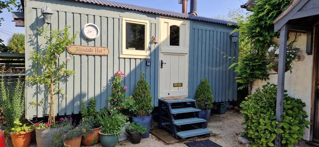 a small shed with plants in front of it at Elmdale Hut - Shepherds Hut in Yatton