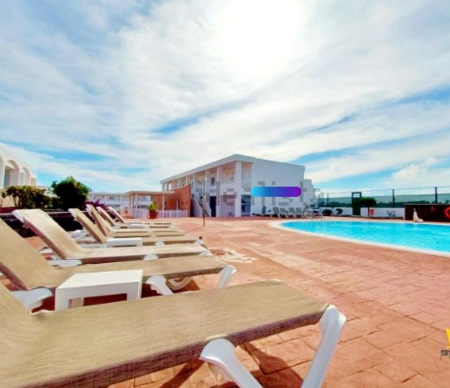 a row of lounge chairs next to a swimming pool at Costa Teguise II in Teguise