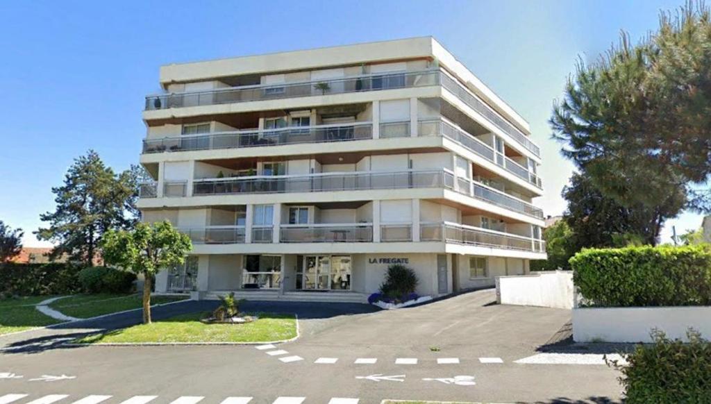 un gran edificio de apartamentos blanco con aparcamiento en Vaux sur Mer - Quartier de PONTAILLAC - APPARTEMENT résidence LA FREGATE en Vaux-sur-Mer