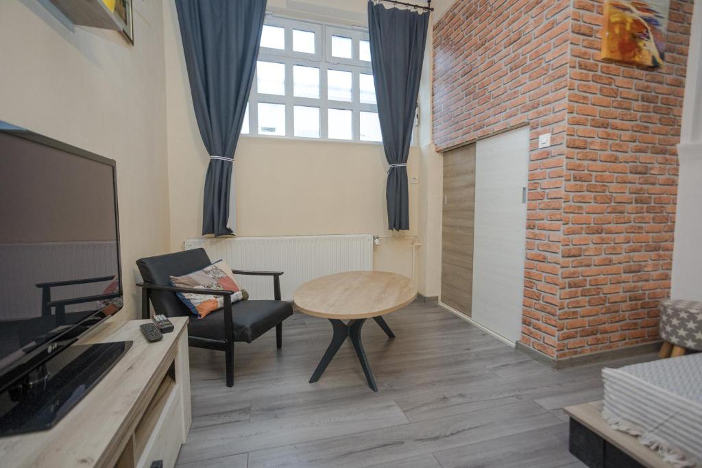 sala de estar con mesa y pared de ladrillo en Studio apartman Kamenčić, en Osijek