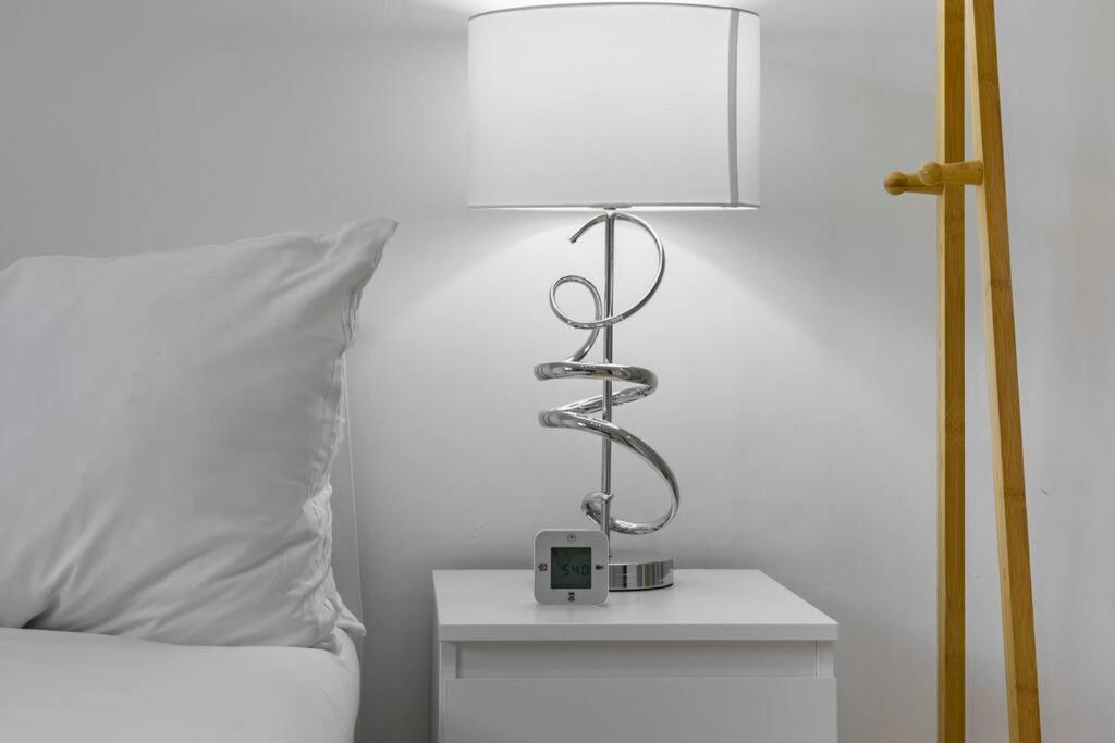 a lamp on a side table next to a bed at 2-BR London Oasis in Woolwich in London