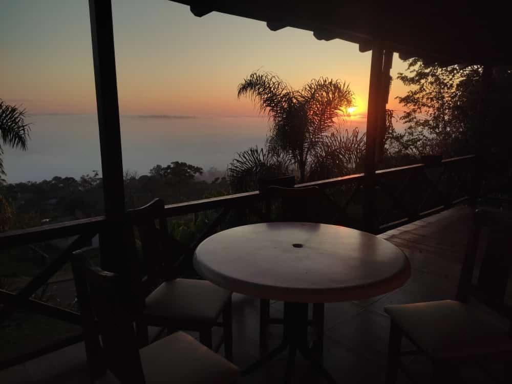 d'une table et de chaises sur un balcon avec vue sur le coucher du soleil. dans l'établissement Cabaña Las Palmeras, à El Soberbio