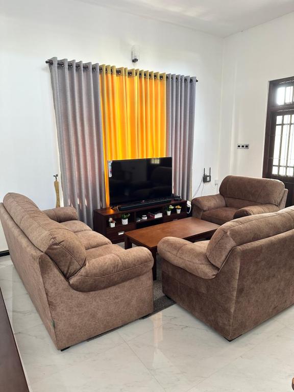 ein Wohnzimmer mit 2 Sofas und einem Flachbild-TV in der Unterkunft The Kandyan Secret Villa - Free Pick up From Kandy Railway Station in Kandy