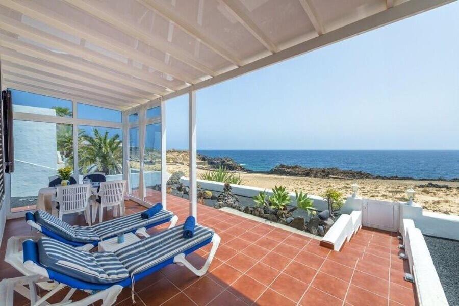 a patio with chairs and a table and the ocean at Casa Salida del Sol in Charco del Palo