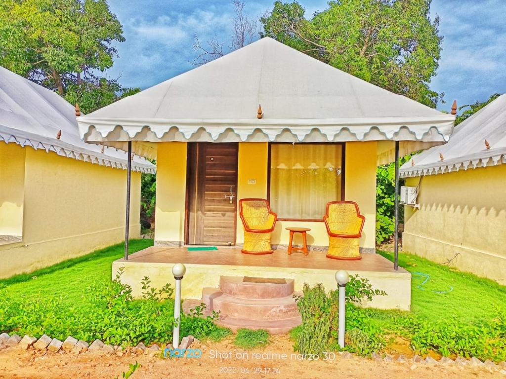 een geel huis met twee stoelen en een tafel bij Nature Resort & Camps - A Luxury Camps in Pushkar