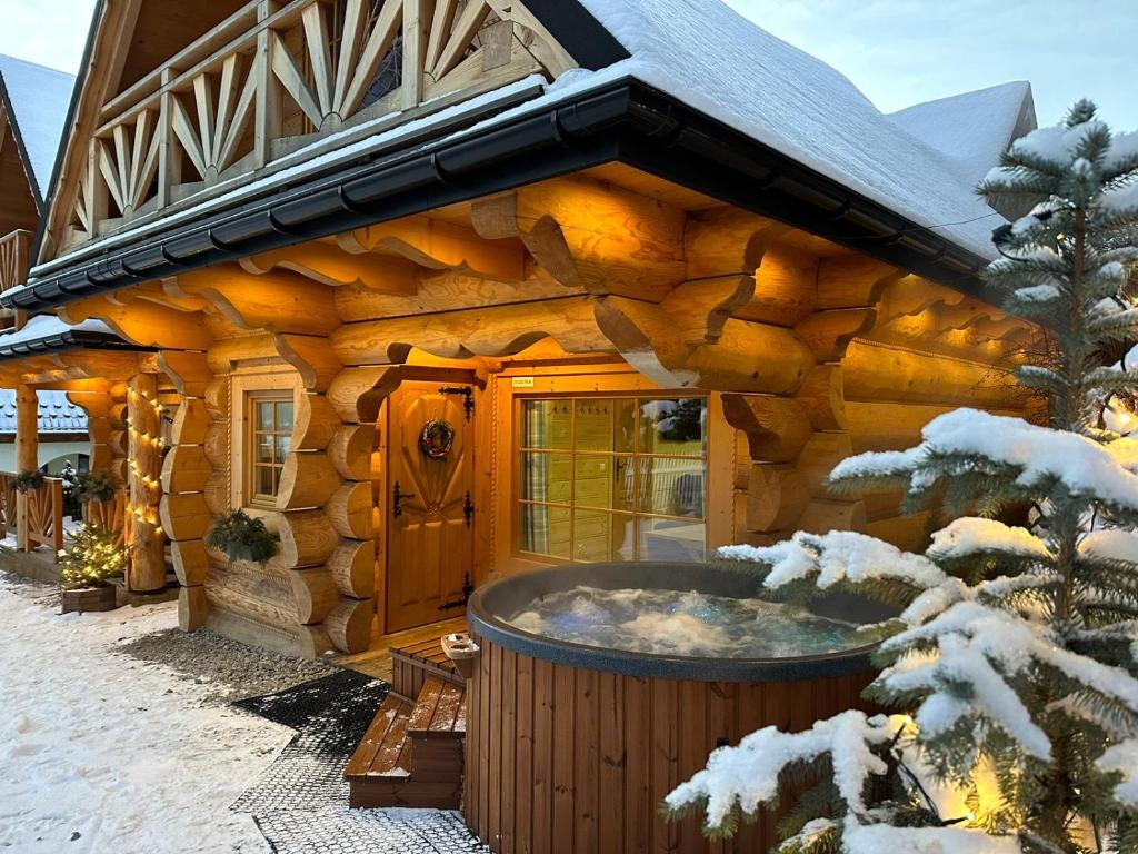 a log cabin with a hot tub in front of it at Wierchowe Domki z jacuzzi in Kościelisko