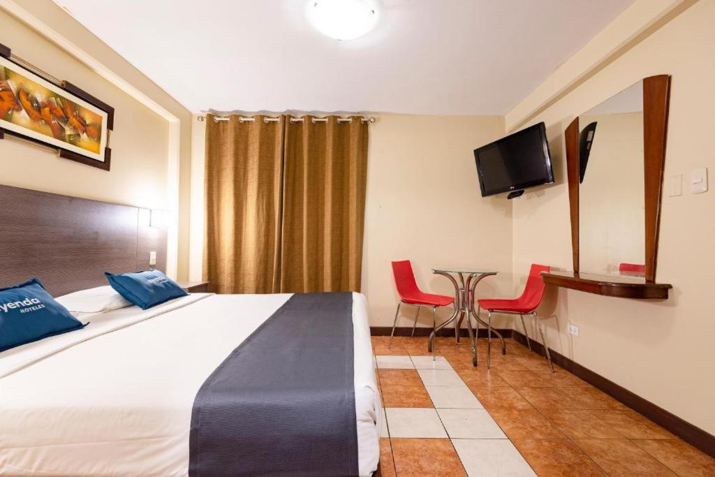 Habitación de hotel con cama, mesa y sillas en Hotel Caribe, en Lima