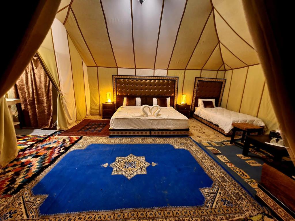 a bedroom with a tent with a bed and a blue rug at Sahara Luxury Camp in Merzouga