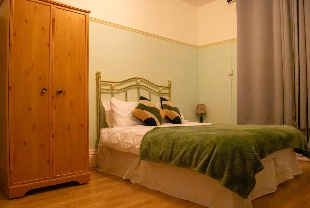 ロンドンにあるCosy Studioのベッドルーム1室(ベッド1台、緑の毛布付)