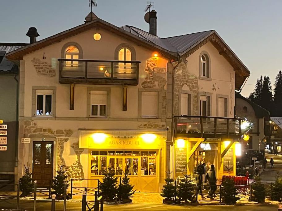 un grand bâtiment avec des personnes debout à l'extérieur dans l'établissement Très beau F2 au cœur du village, aux Rousses