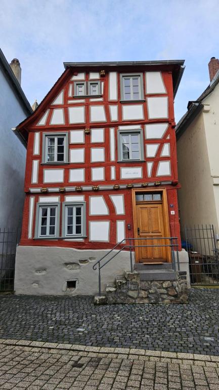 ein rotes und weißes Haus mit einer Holztür in der Unterkunft Altstadt Märchen-Fachwerkhaus in Limburg an der Lahn