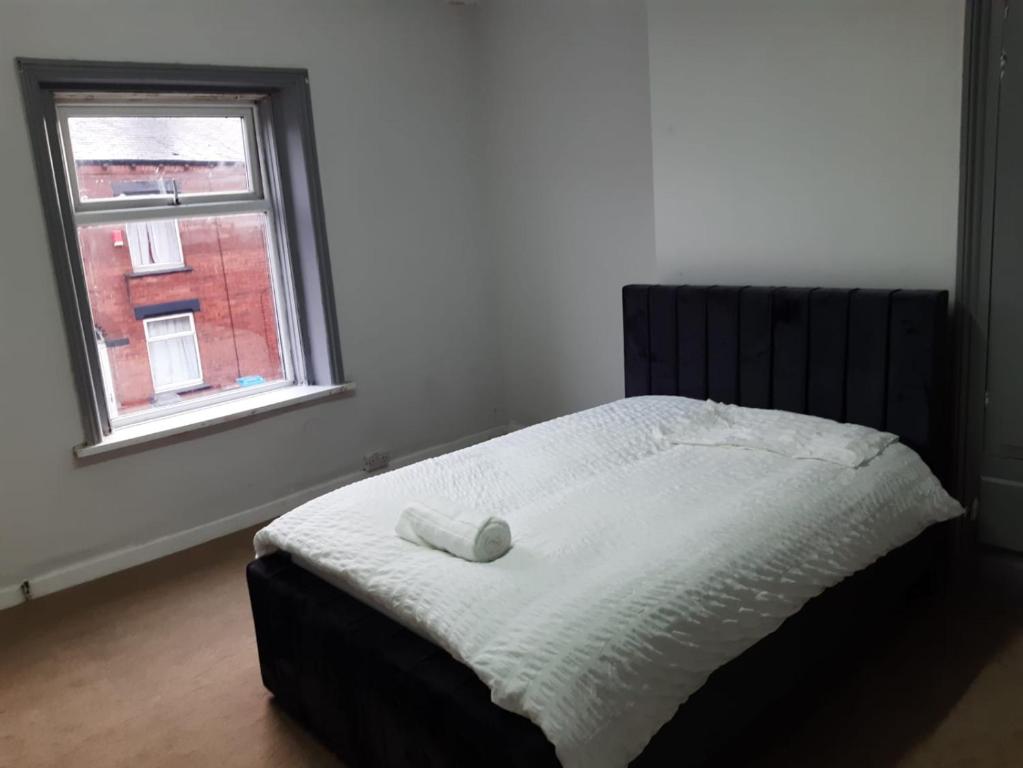 Bett in einem Schlafzimmer mit Fenster in der Unterkunft Cozy large double RM 10 in Oldham