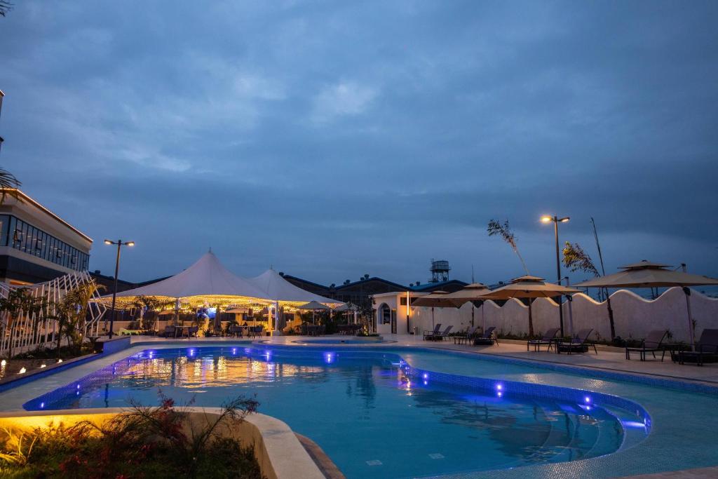 a large swimming pool at night with umbrellas at Argyle Grand Hotel Nairobi Airport in Nairobi