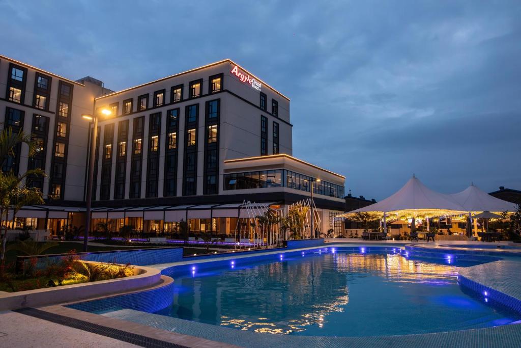 a hotel with a swimming pool in front of a building at Argyle Grand Hotel Nairobi Airport in Nairobi