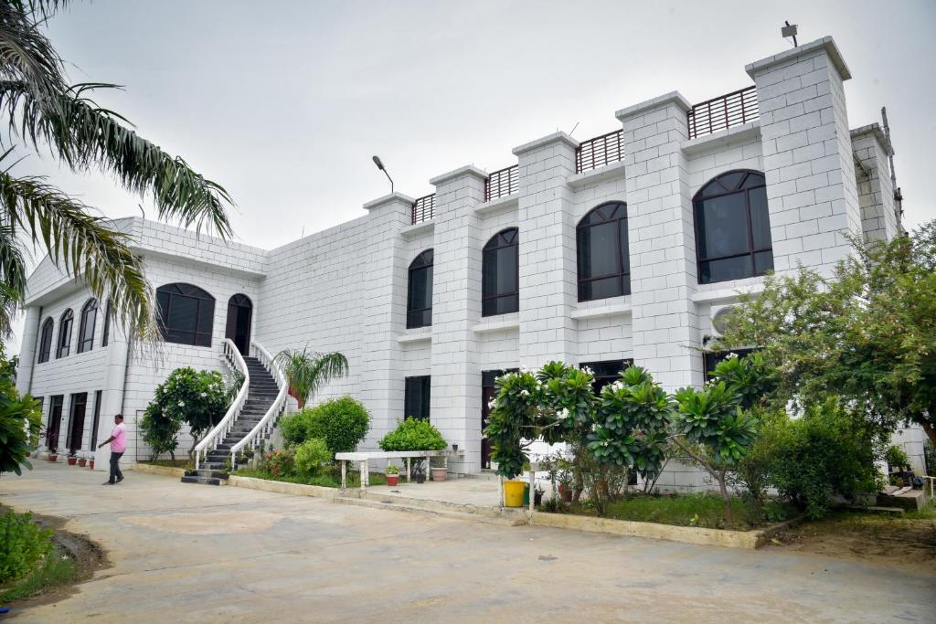 a man is standing in front of a white building at International Shri Vidya Peetham (ISVP) in Lucknow