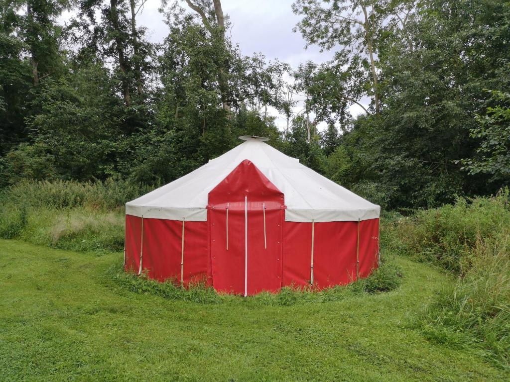 uma tenda vermelha e branca no meio de um campo em Jurten im Garten Eden BUB em Gützkow