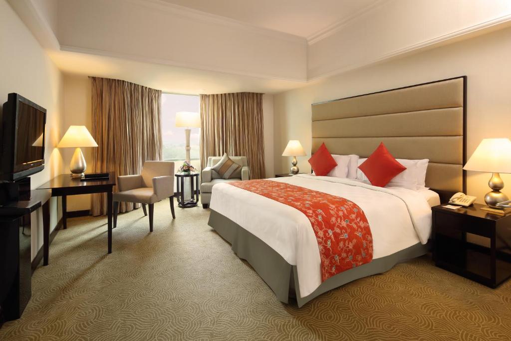 a hotel room with a large bed and a television at Aryaduta Pekanbaru in Pekanbaru