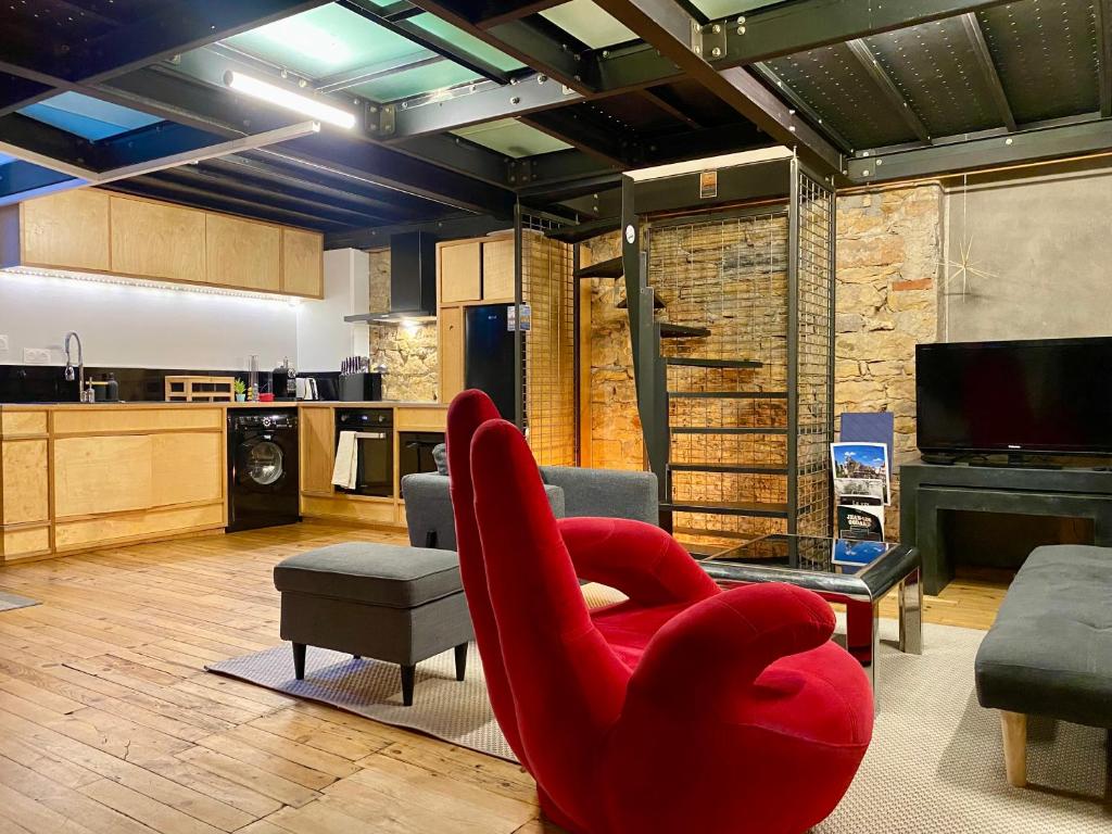 Hotel Loft moderne & cosy Terreaux / Croix Rousse - Courts et longs séjours, a living room with a red chair and a kitchen at Loft moderne & cosy Terreaux / Croix Rousse - Courts et longs séjours in Lyon