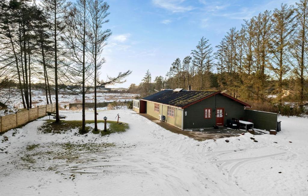 ein kleines Haus im Schnee mit einem Zaun in der Unterkunft Gorgeous Home In Lkken With Kitchen in Løkken