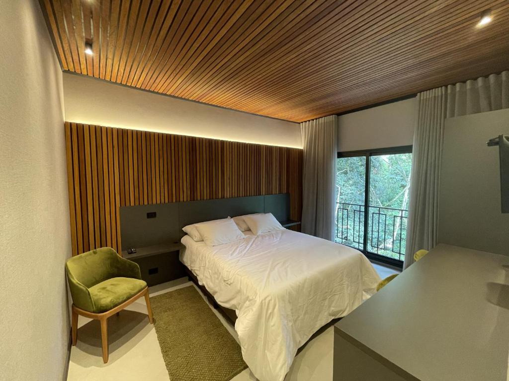 ein Schlafzimmer mit einem Bett, einem Stuhl und einem Fenster in der Unterkunft Pousada Encontro das Águas in Gonçalves