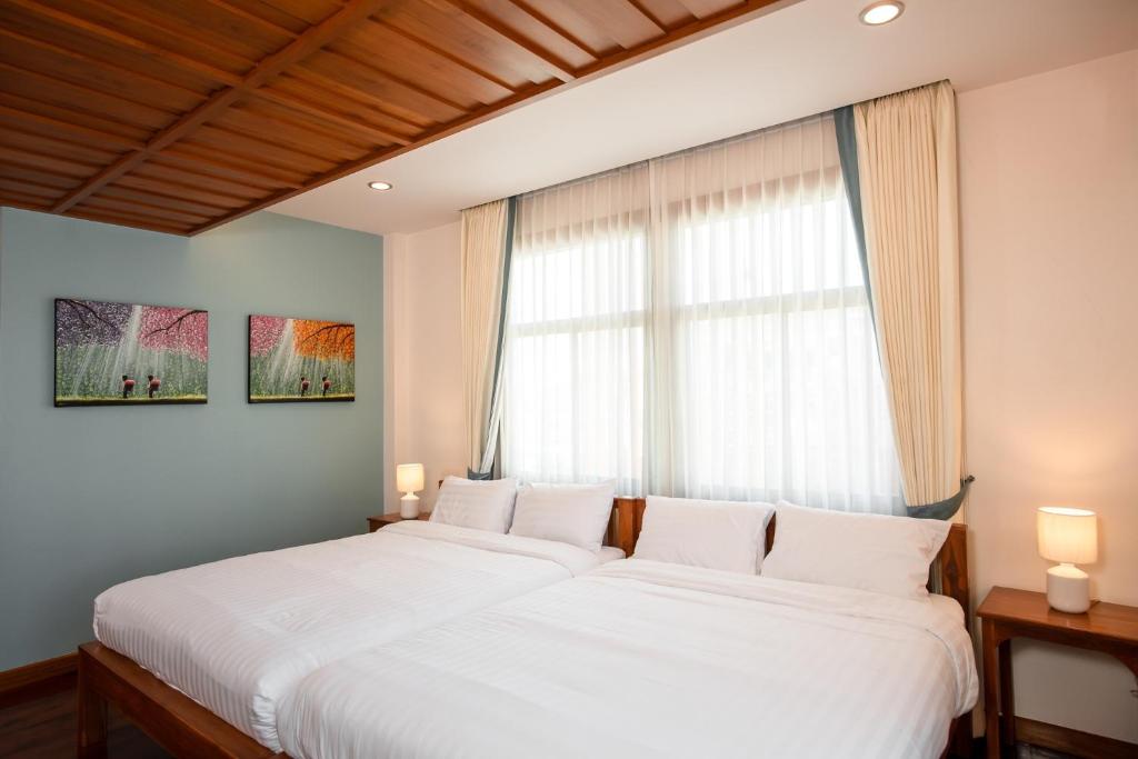 1 dormitorio con 2 camas blancas y ventana en HUAN CHOM JAN Hometel at Lampang 