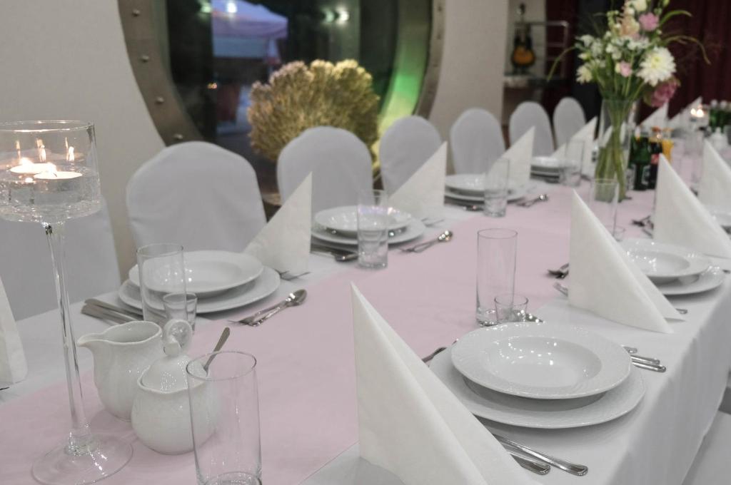 einen weißen Tisch mit weißen Tellern und Weingläsern in der Unterkunft Hotel i Restauracja - Jastrzębia Góra in Puck