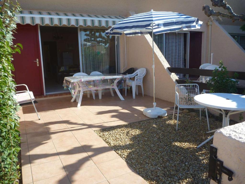 eine Terrasse mit einem Sonnenschirm, einem Tisch und Stühlen in der Unterkunft Appartement Marseillan-Plage, 3 pièces, 6 personnes - FR-1-387-134 in Le Castellas