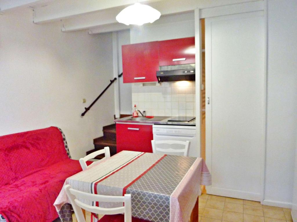 a small kitchen with a table and a red couch at Appartement Marseillan-Plage, 2 pièces, 5 personnes - FR-1-387-167 in Marseillan