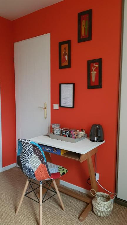 a desk and a chair in a room with an orange wall at Chez Laurence &amp; RV in Vauréal