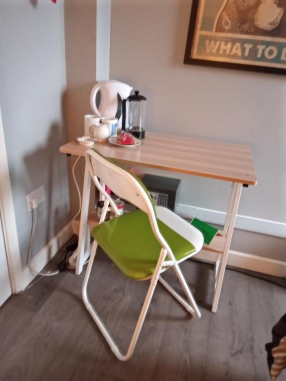 a desk with a green chair and a wooden table at Bromley in Bickley