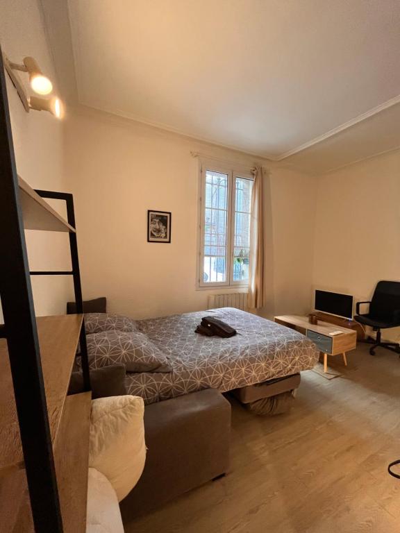 a bedroom with a bed and a couch and a window at Le studio des carmes in Nîmes