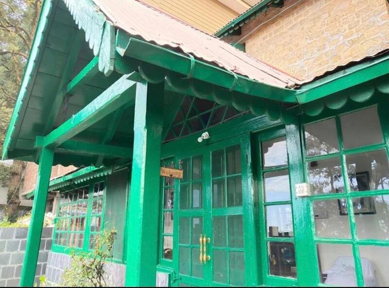 a green building with windows and a roof at Cottage Villa Dalhousie in Dalhousie