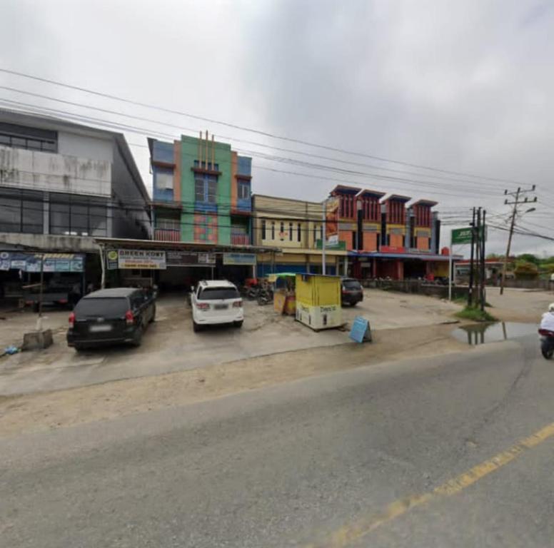 a city street with cars parked in a parking lot at GreenKOST in Sintang