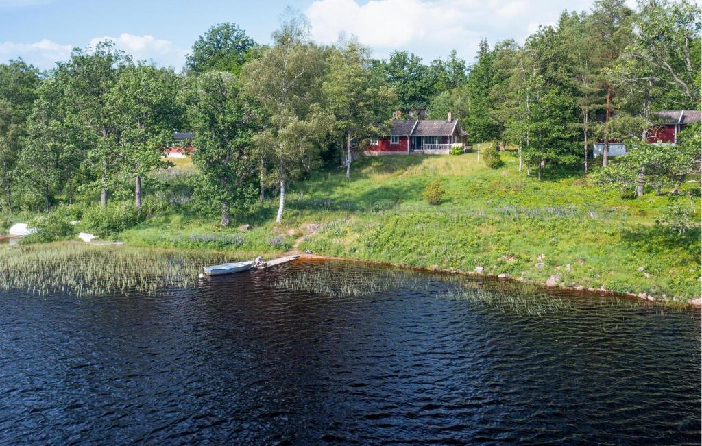 a boat on a lake with a house in the background at Amazing Home In Gislaved With 4 Bedrooms, Sauna And Wifi in Hornbetan