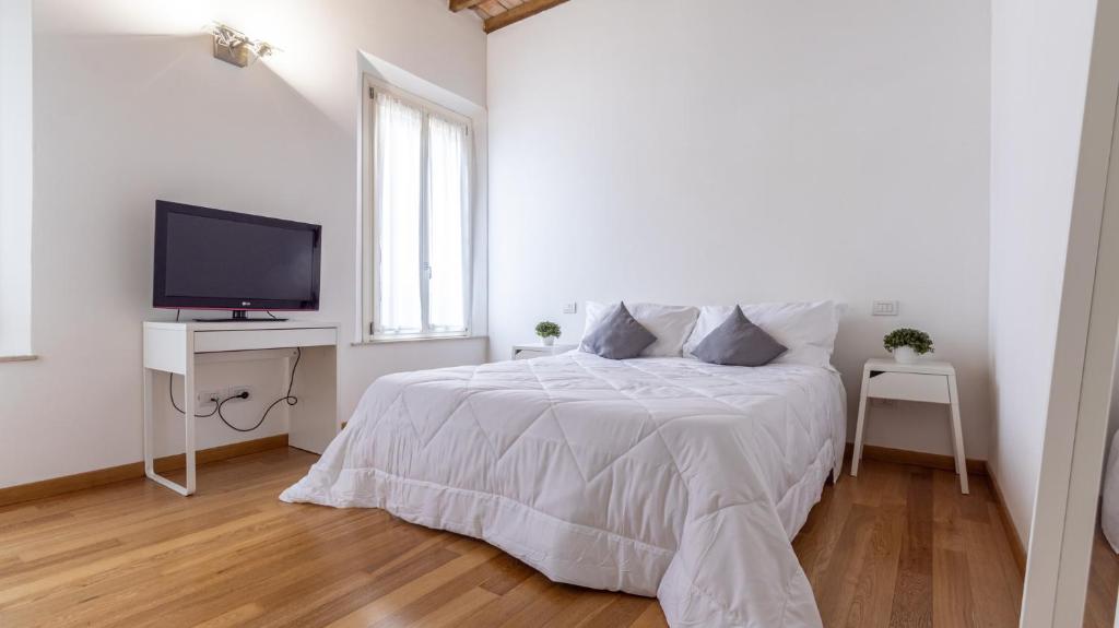 ein weißes Schlafzimmer mit einem Bett und einem TV in der Unterkunft [Piazza Martiri]-In pieno centro sotto al Castello in Carpi
