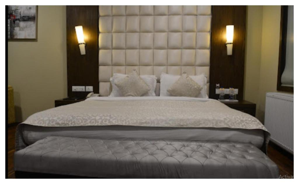 um quarto com uma cama grande e uma grande cabeceira. em Spring Vine Shrinagar em Srinagar
