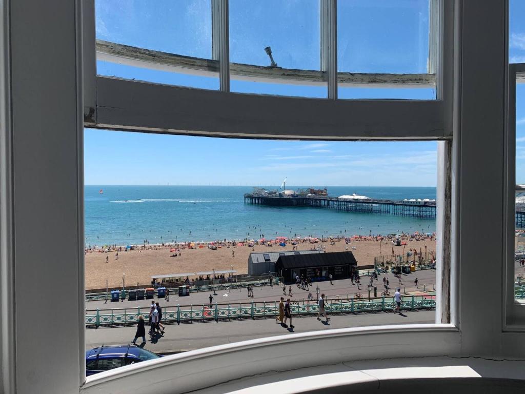 een raam met uitzicht op een strand en een pier bij Seaview Regency Apartment With Private Parking in Brighton & Hove