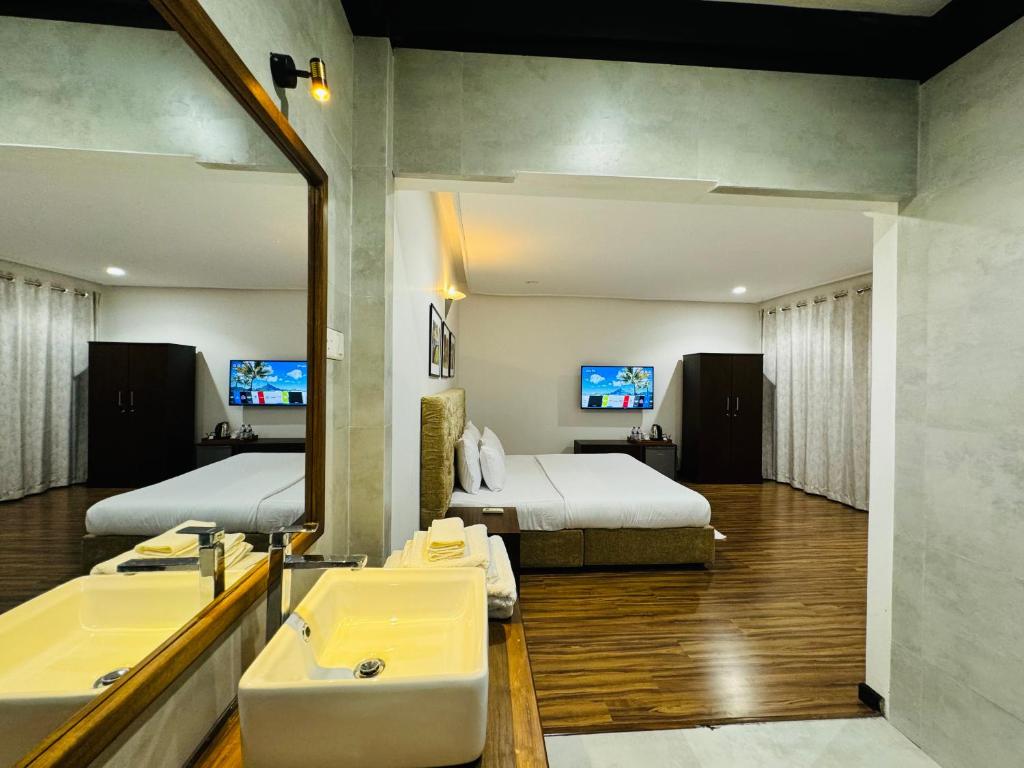 uma casa de banho com 2 camas, um lavatório e um espelho. em Beverly Beach Mirissa em Mirissa
