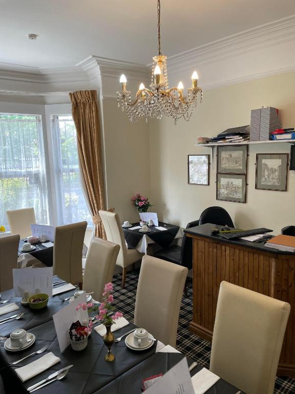 a dining room with tables and chairs and a chandelier at Burton Villa Guest House in York